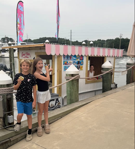 Kids with cookies and treats in front of the Ice Cream Afloat boat and its pink scalloped awning