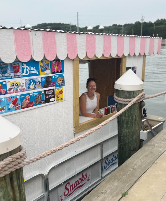 The serving window of the Ice Cream Afloat boat with its pink and white scalloped awning and ice cream menu board