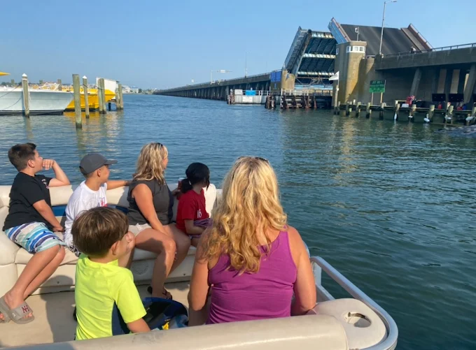 Family on a pontoon boat heading under the drawbridge on the Ocean City MD bay